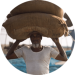 Fish farmer carry sacks of dry fish on their heads preparing to sail to market, Mousuni Island, Sundarbans, India